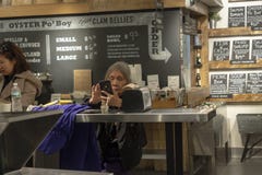 CHELSEA MARKNAD, NEW YORK CITY, USA - 14 MAJ 2018: En gammal kvinna som kontrollerar hennes smartphone i Chelsea Market royaltyfri foto CHELSEA MARKNAD, NEW YORK CITY, USA - 14 MAJ 2018: En gammal kvinna som kontrollerar hennes smartphone i Chelsea Market royaltyfri foto