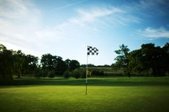 Chequered flag on a golf course green with a blue sky stock photography Chequered flag on a golf course green with a blue sky stock photography
