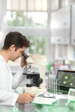 Chercheur masculin avec le microscope dans l'installation moderne de recherches image libre de droits Chercheur masculin avec le microscope dans l'installation moderne de recherches image libre de droits