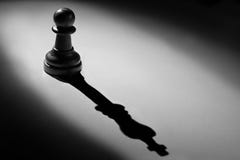Chess pawn standing in a spotlight shadow of king Stock Image Chess pawn standing in a spotlight shadow of king Stock Image