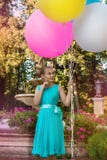 Chica joven bonita con los globos coloridos grandes que camina en el parque cerca de la ciudad - imagen fotografía de archivo Chica joven bonita con los globos coloridos grandes que camina en el parque cerca de la ciudad - imagen fotografía de archivo