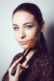 Chica joven de la belleza con los cepillos del maquillaje Natural compense a la mujer morena con los ojos del bleu Cara hermosa m fotografía de archivo Chica joven de la belleza con los cepillos del maquillaje Natural compense a la mujer morena con los ojos del bleu Cara hermosa m fotografía de archivo
