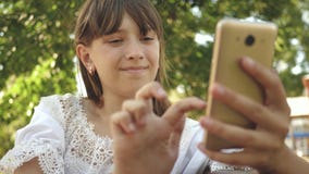 Chica joven que charla en una tableta con los amigos la muchacha hermosa escribe en smartphone una letra en parque en la primaver metrajes Chica joven que charla en una tableta con los amigos la muchacha hermosa escribe en smartphone una letra en parque en la primaver metrajes
