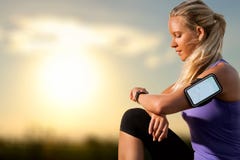 Chica joven que comprueba entrenamiento en el reloj elegante en la puesta del sol imagen de archivo Chica joven que comprueba entrenamiento en el reloj elegante en la puesta del sol imagen de archivo