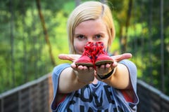 Chica joven que se sostiene en ambos pequeños zapatos de bebé rojos de los brazos extendidos fotos de archivo Chica joven que se sostiene en ambos pequeños zapatos de bebé rojos de los brazos extendidos fotos de archivo