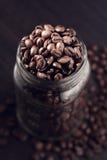 Chicchi di caffè che si rovesciano fuori da un barattolo immagine stock Chicchi di caffè che si rovesciano fuori da un barattolo immagine stock