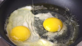 A chicken eggs are frying in butter in a fraying pan