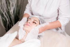 Chiffon avec le visage stérile de serviette Jeune jolie femme recevant des traitements dans des salons de beauté Mousse de nettoy image libre de droits Chiffon avec le visage stérile de serviette Jeune jolie femme recevant des traitements dans des salons de beauté Mousse de nettoy image libre de droits