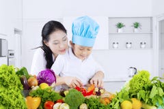 Child cutting vegetables with her mother royalty free stock photography Child cutting vegetables with her mother royalty free stock photography