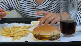 Child eating fast food, kid eats hamburger in restaurant, girl drinking juice stock video footage Child eating fast food, kid eats hamburger in restaurant, girl drinking juice stock video footage