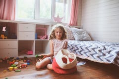 child girl cleaning her room and organize wooden toys into knitted storage bag Stock Photo child girl cleaning her room and organize wooden toys into knitted storage bag Stock Photo