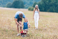 Child with his parents pushing a whellbarrow outdoors royalty free stock images Child with his parents pushing a whellbarrow outdoors royalty free stock images
