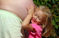 Child hugging mom pregnant belly