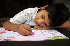 Child is playing with drawing books. Child coloring. Thoughtful expression.