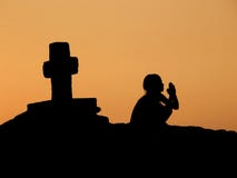 Child, prayer, cross in sunset