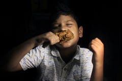 Child with yummy chicken roast. Child having a chicken drumstick to eat.