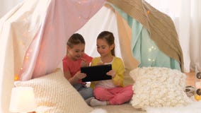 Little girls with tablet pc in kids tent at home