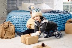 Children brother and sister sitting on floor in bedroom near bed the girl is stretching to the box with a gift on the background o stock photography Children brother and sister sitting on floor in bedroom near bed the girl is stretching to the box with a gift on the background o stock photography