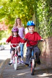 Children Riding Bikes On Their Way To School With Mother stock image Children Riding Bikes On Their Way To School With Mother stock image