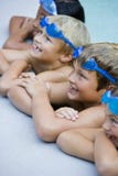 Children smiling, hanging on side of swimming pool