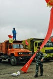 chinese soldier walking past by some heavy duty trucks with a worker on top waving the national red flag stock image chinese soldier walking past by some heavy duty trucks with a worker on top waving the national red flag stock image