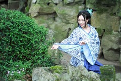 Chinese woman in traditional Blue and white porcelain style Hanfu dress. Sit on stone at Qiyuan Garden. Qiyuan Garden is one of the ten famous gardens in Stock Photography Chinese woman in traditional Blue and white porcelain style Hanfu dress. Sit on stone at Qiyuan Garden. Qiyuan Garden is one of the ten famous gardens in Stock Photography