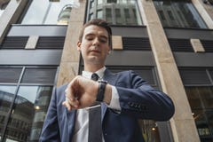 Chiuda su del telefono cellulare della tenuta dell'uomo d'affari a disposizione ed esaminando gli orologi fotografia stock libera da diritti Chiuda su del telefono cellulare della tenuta dell'uomo d'affari a disposizione ed esaminando gli orologi fotografia stock libera da diritti