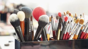 Chiuda su delle spazzole, strumenti di trucco sulla tavola nello spogliatoio video d archivio Chiuda su delle spazzole, strumenti di trucco sulla tavola nello spogliatoio video d archivio