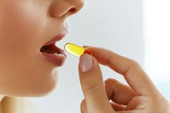 Chiuda su di bella donna che prende la capsula dell'olio di pesce in bocca Immagine Stock Libera da Diritti Chiuda su di bella donna che prende la capsula dell'olio di pesce in bocca Immagine Stock Libera da Diritti
