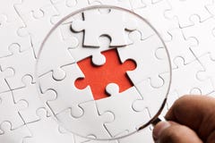 CHIUDA sui pezzi di puzzle con una lente d'ingrandimento. Immagine di concetto di rilevazione del difetto. immagine stock libera da diritti CHIUDA sui pezzi di puzzle con una lente d'ingrandimento. Immagine di concetto di rilevazione del difetto. immagine stock libera da diritti