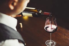 Chiuda sul colpo del sommelier che versa il vino rosso da imbottigliano il vetro immagine stock libera da diritti Chiuda sul colpo del sommelier che versa il vino rosso da imbottigliano il vetro immagine stock libera da diritti