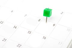 Chiuda sul perno verde sul calendario bianco immagine stock Chiuda sul perno verde sul calendario bianco immagine stock