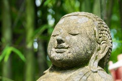 Chiuda sulla testa Buddha scolpito dalla pietra in parco di bambù fotografia stock Chiuda sulla testa Buddha scolpito dalla pietra in parco di bambù fotografia stock
