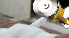 Chiuda sulle mani del colpo dell'uomo che usando la smerigliatrice elettrica a tagliare il tubo di alluminio bianco video d archivio Chiuda sulle mani del colpo dell'uomo che usando la smerigliatrice elettrica a tagliare il tubo di alluminio bianco video d archivio