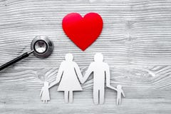 Choose health insurance. Stethoscope, paper heart and silhouette of family on grey wooden background top view copyspace stock image Choose health insurance. Stethoscope, paper heart and silhouette of family on grey wooden background top view copyspace stock image