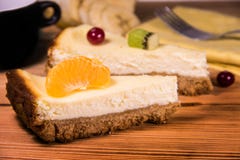 Chopped cheesecake on a wooden table with fruit, a towel and a cup of coffee royalty free stock photo Chopped cheesecake on a wooden table with fruit, a towel and a cup of coffee royalty free stock photo