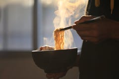 Chopsticks εκμετάλλευσης χεριών ατόμων των στιγμιαίων νουντλς στο ξύλινο κύπελλο με τον καπνό που αυξάνεται στο σπίτι, αποτυχία ν στοκ εικόνα Chopsticks εκμετάλλευσης χεριών ατόμων των στιγμιαίων νουντλς στο ξύλινο κύπελλο με τον καπνό που αυξάνεται στο σπίτι, αποτυχία ν στοκ εικόνα