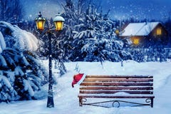 Christmas art card. Santa hat on a bench in the snow against the background of the Christmas winter forest. Village house in the b