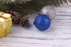 Christmas background with golden gift box red and silver balls natural fir branches cones on white wooden stock photography Christmas background with golden gift box red and silver balls natural fir branches cones on white wooden stock photography
