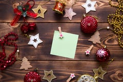 Christmas flat lay of red balloons and wooden stars and clothespins on a dark background with a square sheet for notes in the cent
