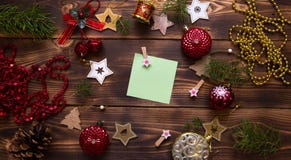 Christmas flat lay of red balloons and wooden stars and clothespins on a dark background with a square sheet for notes in the cent