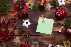 Christmas flat lay of red balloons and wooden stars and clothespins on a dark background with a square sheet for notes in the