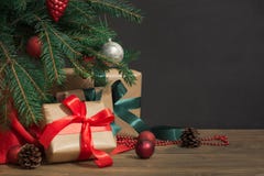 Christmas holiday background. Gifts with a red ribbon, Santa`s hat and decor under a Christmas tree on a wooden board. stock photo Christmas holiday background. Gifts with a red ribbon, Santa`s hat and decor under a Christmas tree on a wooden board. stock photo