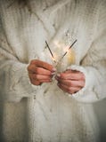Woman in sweater holding Christmas sparklers in hands, close-up royalty free stock image Woman in sweater holding Christmas sparklers in hands, close-up royalty free stock image
