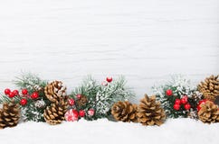 Christmas snow scene. Christmas tree branches with cones and ornaments on wooden light background,