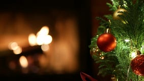 Christmas tree lights by fire in fireplace, New Year or Xmas decoration of pine.