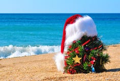 Christmas tree and santa hat on sand on beach stock photography Christmas tree and santa hat on sand on beach stock photography