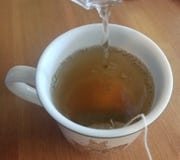 Chá verde quente que está sendo fabricado cerveja em um copo branco fotografia de stock Chá verde quente que está sendo fabricado cerveja em um copo branco fotografia de stock