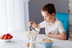 Chłopiec sumujący cukier biały ser w pucharze dla cheesecake Obrazy Stock Chłopiec sumujący cukier biały ser w pucharze dla cheesecake Obrazy Stock