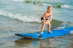 Chłopiec surfing na tropikalnej plaży Dziecko na kipieli desce na ocean fala Aktywni wodni sporty dla dzieciaków Dzieciaka dopłyn obrazy stock Chłopiec surfing na tropikalnej plaży Dziecko na kipieli desce na ocean fala Aktywni wodni sporty dla dzieciaków Dzieciaka dopłyn obrazy stock